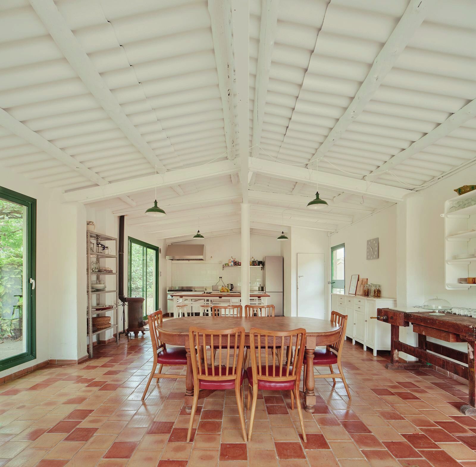 Large kitchen and dining room with a white-beamed ceiling, oval table and terracotta floor